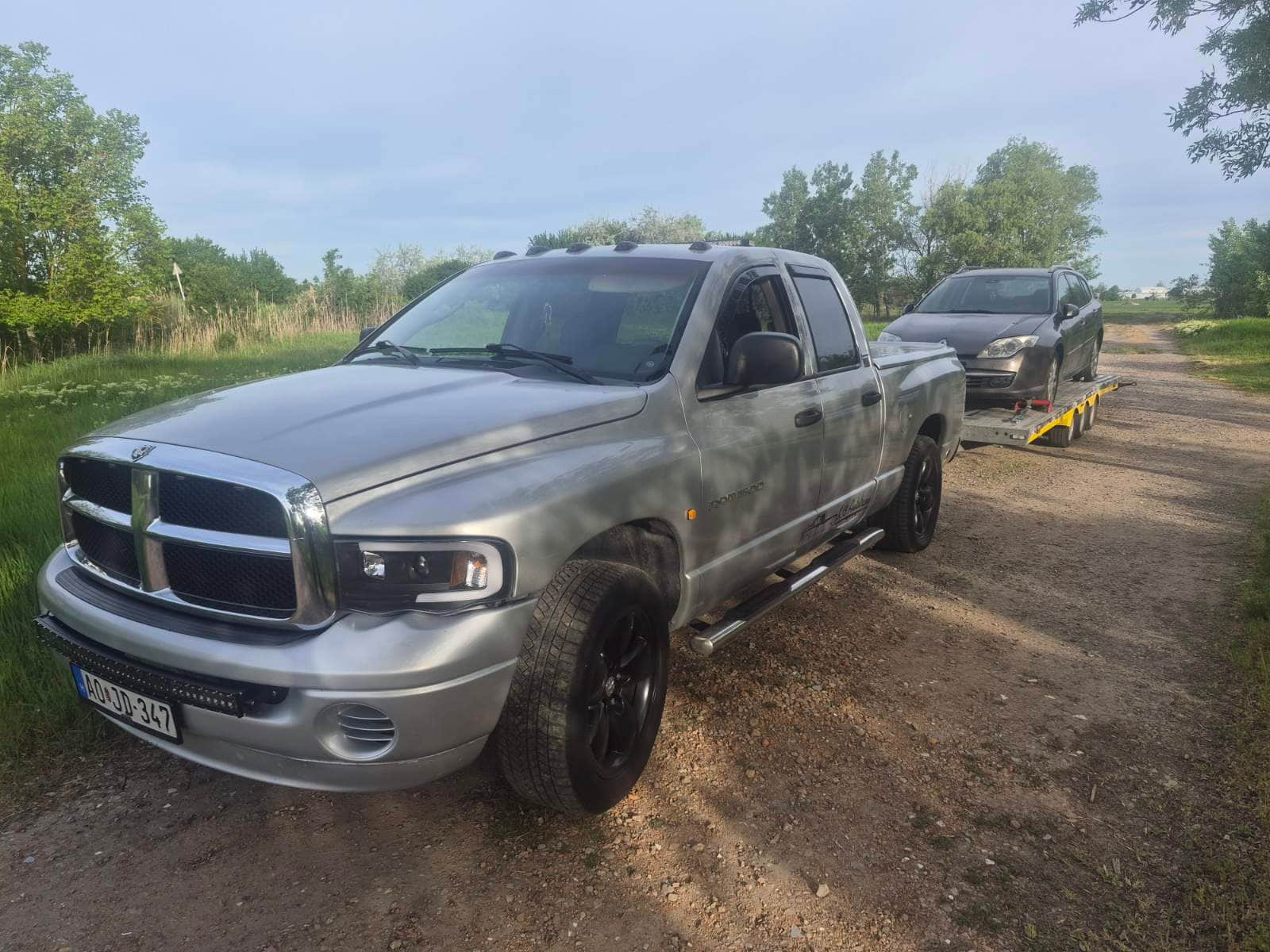 Ezüst Dodge Ram pickup trélerrel földúton, elszállított autóval