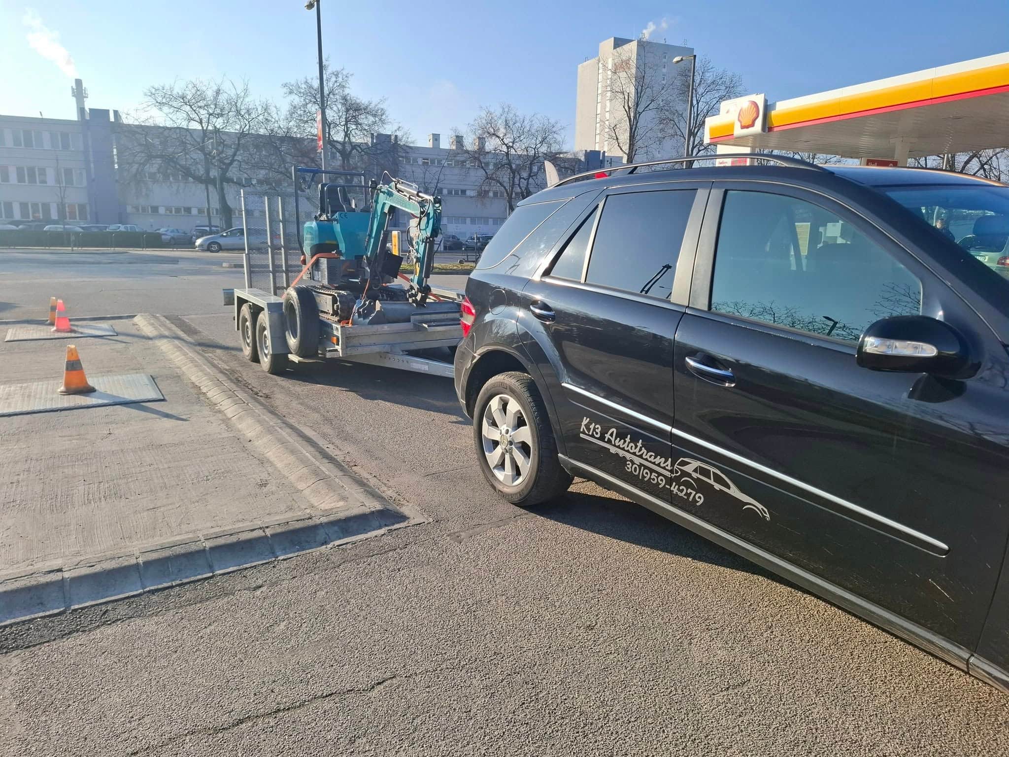 Kis munkagép szállítása tréleren egy benzinkútnál