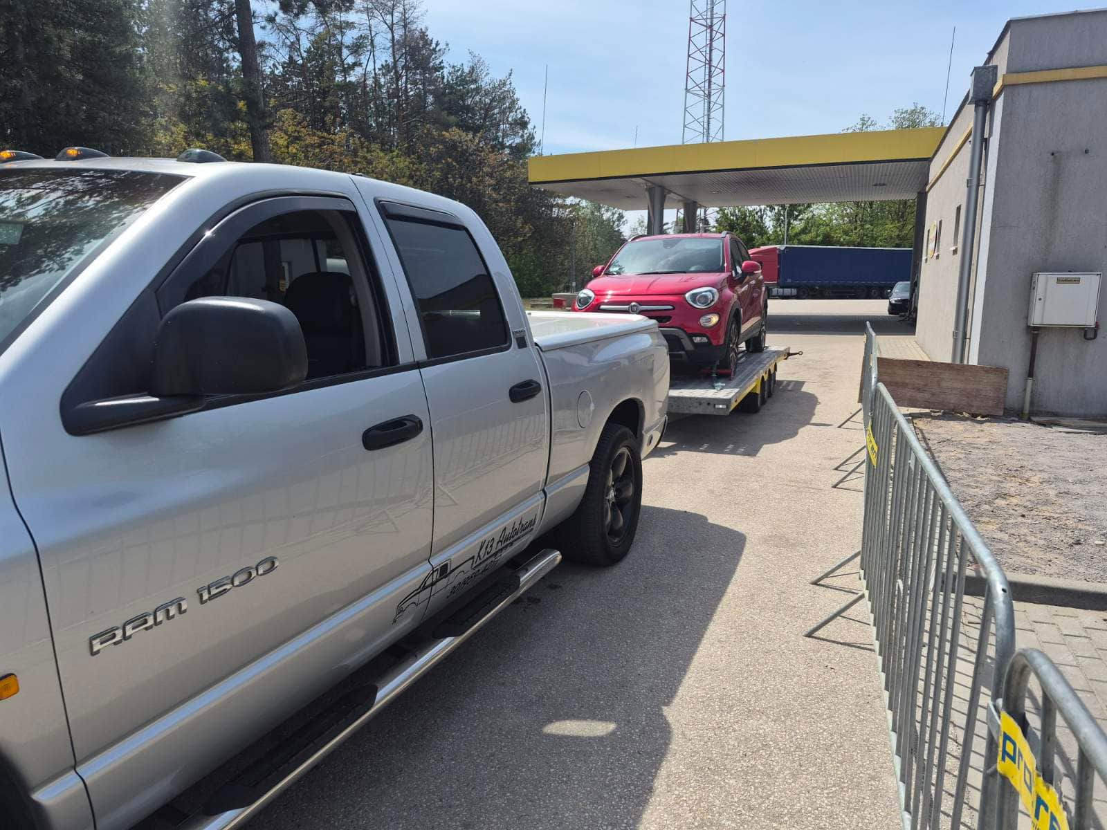 Piros Fiat 500 tréleren, az ezüst Dodge Ram pickup vontatja
